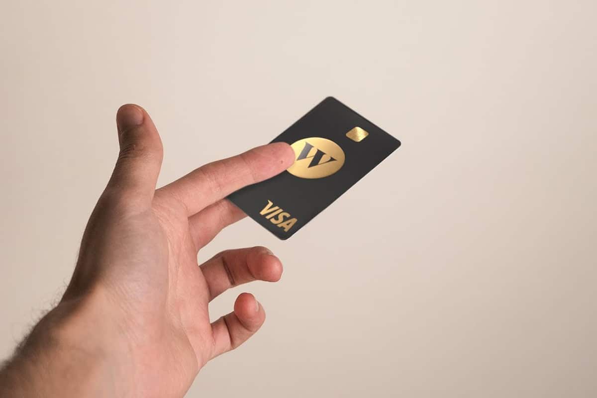 Model holding the Wealthsimple Cash card, in black with gold lettering and trim.