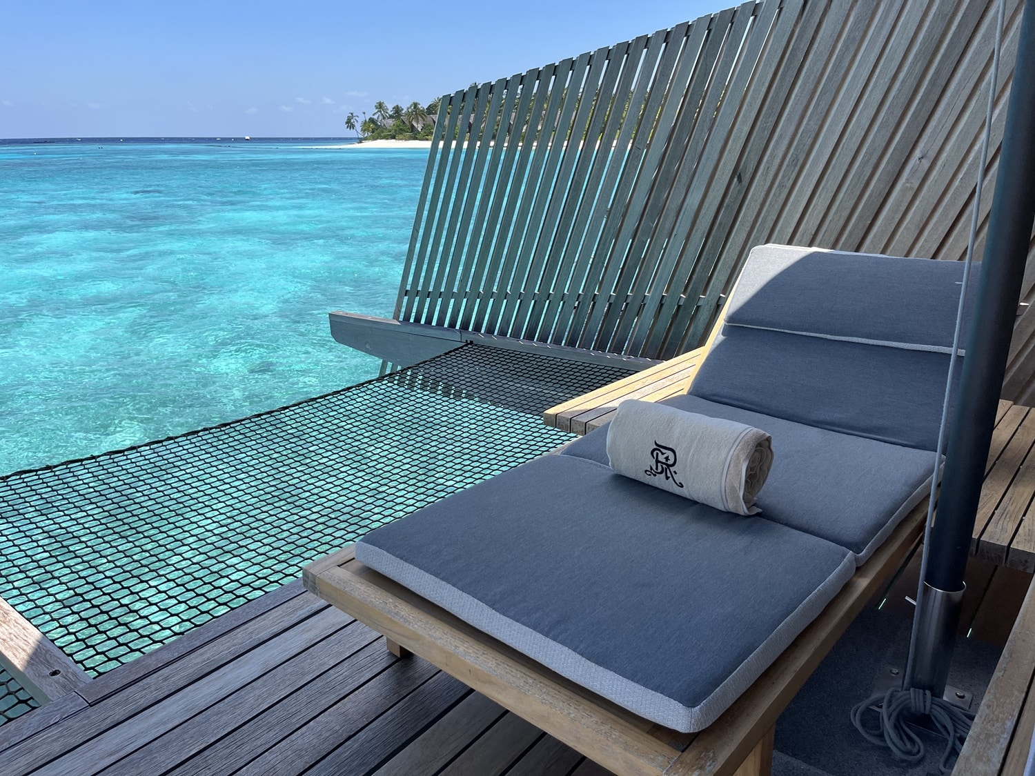st regis maldives vommuli resort overwater bungalow lounge chair with netting