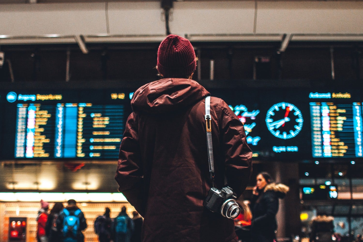 person standing in airport looking at departures board