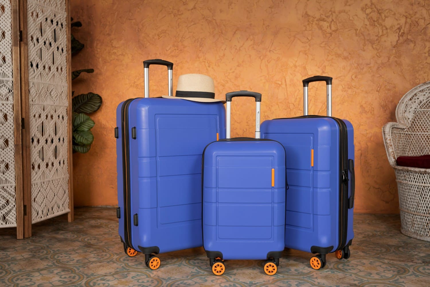 three pieces of blue luggage against wall
