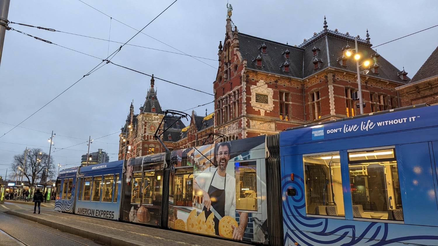 Train stopped at Amsterdam central station with Amex branding.