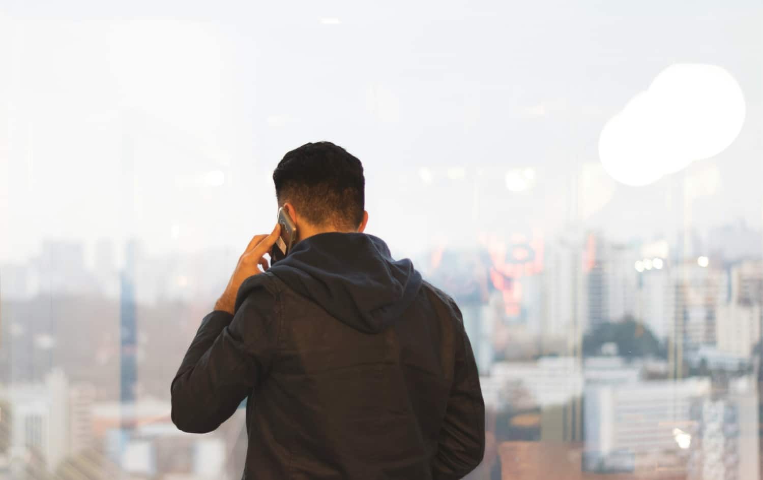 person on cellphone with city in distance